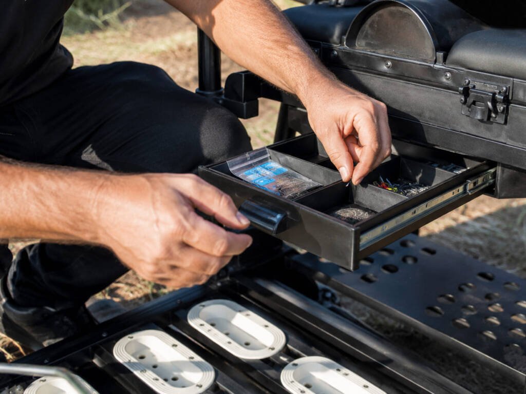 Pescatore che prende ami e accessori dal cassetto del paniere da pesca Morgana